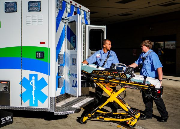 two paramedics with LACP loading stretcher into the back on an ambulance